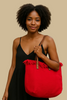 Red canvas tote bag with braided fringe, side view