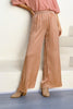 Wide-leg satin striped trousers in golden cream, seated pose